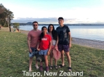 Latinx family of four stand smiling outdoors in beachwear by a lake